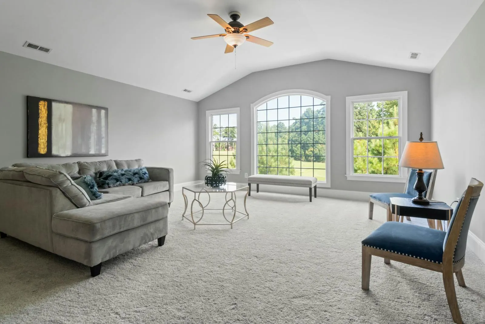 Bright contemporary living room with freshly cleaned plush light-grey carpet, vaulted ceiling, and large windows